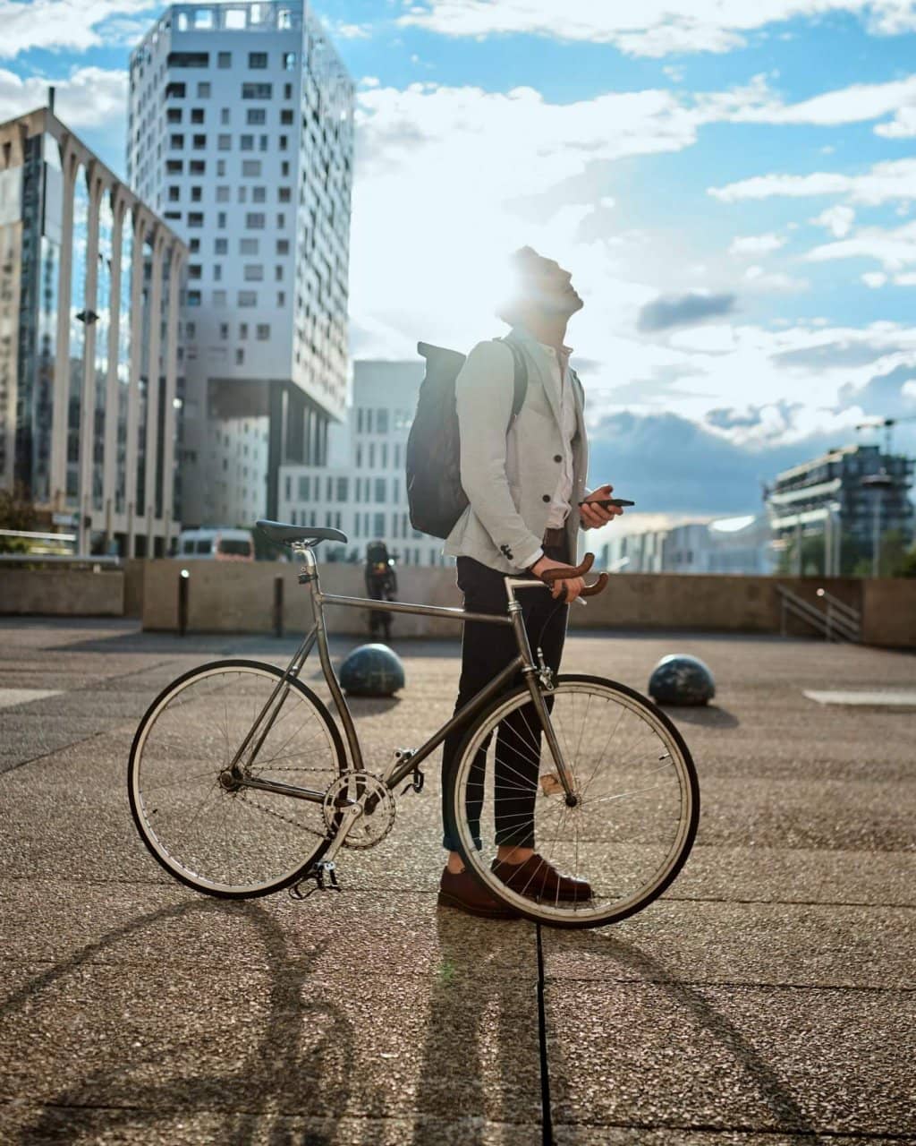 Shot of a young businessman using a smartphone while traveling through the city with his bicycle